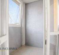 Verklebte Balkonwand in einer 2-Zimmer-Wohnung mit einfachen Fliesen und grauen Wänden.