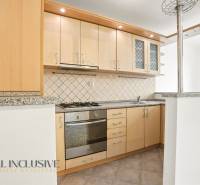 Küche in einer 2-Zimmer-Wohnung mit Holzschränken und einer Arbeitsplatte aus Stein.