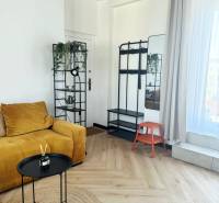 In der 3-Zimmer-Wohnung befinden sich ein senffarbenes Sofa, ein Ständer, ein Spiegel und ein Boden mit Holzdekor.