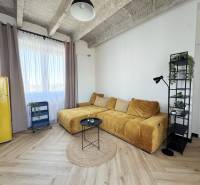 Wohnzimmer mit Holzboden, gelbem Sofa und Retro-Kühlschrank.