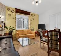 Helles Wohnzimmer mit Kamin, Sofa, Fernseher und Holzboden in einer 3-Zimmer-Wohnung.