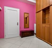 Der Flur in einer 3-Zimmer-Wohnung mit rosa Wänden, weißen Türen und einem Kleiderschrank.