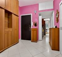 Geräumiger Flur einer 3-Zimmer-Wohnung mit Holzschränken und rosa Wänden.