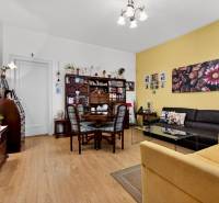 Wohnzimmer mit Holzboden, Bildern, dunkelbraunem Sofa und Esstisch.