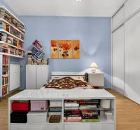 Ein Schlafzimmer mit Holzboden, Regalen voller Bücher und weißen Möbeln.