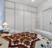 Schlafzimmer mit dekorativer Steppdecke in einer 3-Zimmer-Wohnung mit minimalistischer Einrichtung.