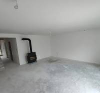 Innenraum eines Einfamilienhauses mit Kamin und Treppe, wartet auf Fertigstellung.