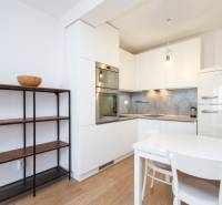 Küche in einer 2-Zimmer-Wohnung mit weißen Schränken, Esstisch und Boden in Holzoptik.