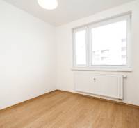 Ein Zimmer in einer 2-Zimmer-Wohnung mit einem Boden in Holzoptik und einem Fenster mit Heizkörper.