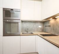 Küche in einer 2-Zimmer-Wohnung mit eingebauten Geräten und einer Küchenzeile mit Holzdekor.