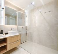 Badezimmer in einer 2-Zimmer-Wohnung mit großem Spiegel und Duschkabine aus Glas.