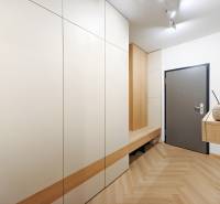 Eingangsflur mit Holzboden in einer 2-Zimmer-Wohnung mit weißen Schränken.