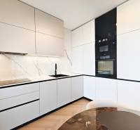 Küche in einer 2-Zimmer-Wohnung mit weißen Schränken und einem Boden in Holzoptik.