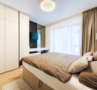 Schlafzimmer in einer 2-Zimmer-Wohnung mit Holzboden, großem Schrank und Vorhängen.