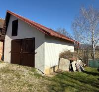 Eine Hütte in Zlaté Moravce mit Holztüren und einem schrägen Dach im Hof.