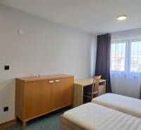 Schlafzimmer mit Betten und Möbeln in einer 3-Zimmer-Wohnung, weiße Wände, Boden mit Holzdekor.