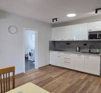 Küche mit weißen Schränken und Geräten in einer 3-Zimmer-Wohnung, Boden mit Holzdekor.