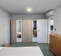 Ein Zimmer in einer 3-Zimmer-Wohnung mit Bett, Schrank, Klimaanlage und Holzmöbeldekor.