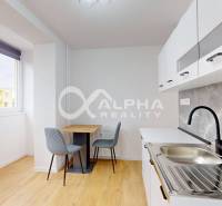 Küche in einer Einzimmerwohnung mit Holzboden und Esstisch.