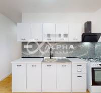 Küche mit weißen Schränken in einer Einzimmerwohnung, Markenküchenherd und Boden mit Holzdekor.