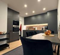 Küche in einer 4-Zimmer-Wohnung mit Holzboden, schwarzen Schränken und Esstisch.