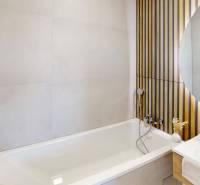 Badezimmer mit Badewanne, Waschbecken und dekorativer Holzverkleidung an der Wand.