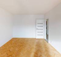 Ein weißer Raum mit einem Boden in Holzoptik und weißen Türen in einer 2-Zimmer-Wohnung.