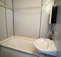 Badezimmer in einer 3-Zimmer-Wohnung mit Badewanne, Waschbecken, einfachen Fliesen und einem Badezimmerschrank.