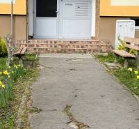 Eingang zum Gebäude in der Škultétyho-Straße in Trebišov mit Bänken und Blumenbeeten.