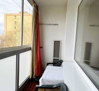 Eine verglaste Loggia in einer 3-Zimmer-Wohnung mit einem Tisch und einem Plastikstuhl.