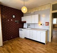 Küche in einer 3-Zimmer-Wohnung mit weißen Schränken und einem Boden in Holzoptik.