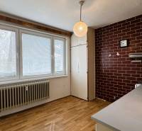 Küche mit Holzboden in einer 3-Zimmer-Wohnung mit braunen Fliesen.