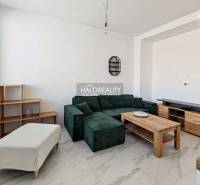 Wohnzimmer mit dunklem Sofa in einer 3-Zimmer-Wohnung mit Fliesenboden und Holzmöbeldekor.