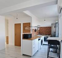 Küche in einer 3-Zimmer-Wohnung mit weißer Küchenzeile, Geräten und Holzelementen.