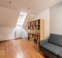 Ein Dachzimmer in einem Einfamilienhaus mit einem Boden in Holzoptik und einem bequemen Sofa.