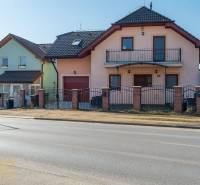 Ein Einfamilienhaus in Poprad mit zwei Etagen, einer Garage und einem Balkon, mit einem Zaun aus Ziegeln.