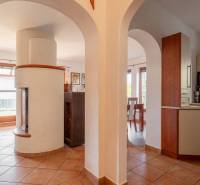 Innenraum eines Einfamilienhauses mit Ziegelboden, bogenförmigen Durchgängen und einem weißen Kamin.