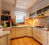 Eine Küche in einem Einfamilienhaus mit eingebauten Geräten, einer Keramikspüle und einem Fenster.