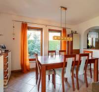 Elfteilige Essgruppe in einem Einfamilienhaus mit orangefarbenen Vorhängen und Fliesen.