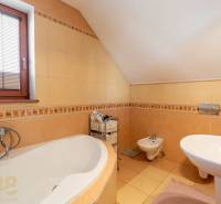 Badezimmer in einem Einfamilienhaus mit Badewanne, Bidet und Fenster mit Jalousien.