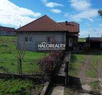 Ein Einfamilienhaus in Rimavské Janovce auf einem Grundstück mit grünem Rasen und Umzäunung.