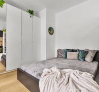 Schlafzimmer in einer Einzimmerwohnung mit Bett, weißem Schrank und Holzboden.