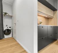 Küche in einer Einzimmerwohnung mit Holzboden und einer Waschmaschine mit Regal.