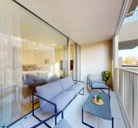 Balkon mit Sitzgelegenheit, Blick auf umliegende Gebäude, Glastüren zu einem Einzimmerapartment.