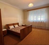 Bett mit Sessel und Nachttischen im heimischen Schlafzimmer mit Teppich.