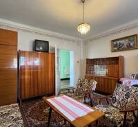 Wohnzimmer in einem Einfamilienhaus mit Teppich, älteren Möbeln und Kronleuchter.