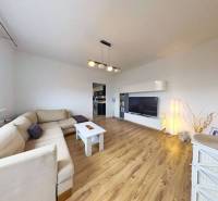 Wohnzimmer mit Holzboden in einer 3-Zimmer-Wohnung mit heller Couch und TV-Schrank.