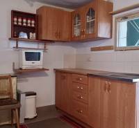 Eine Küche in einer Hütte mit Holzmöbeln und einer Mikrowelle, Boden mit Holzdekor.