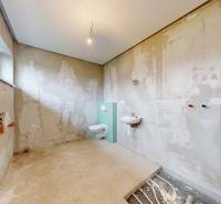 Ein unvollständig fertiggestelltes Badezimmer in einem Einfamilienhaus mit installiertem WC und Waschbecken.