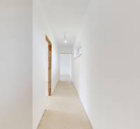 Weißer Flur im Einfamilienhaus mit unfertigem Boden und glatten Wänden.